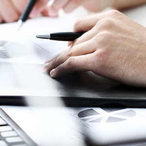 ręka z długopisem opiera się na stole